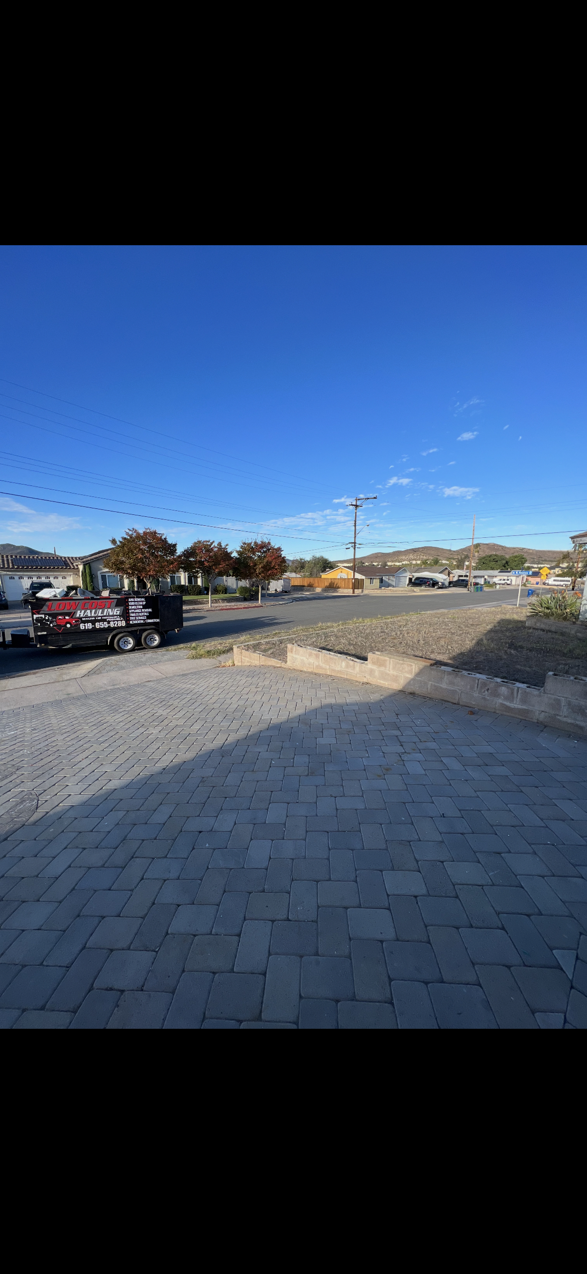 Low Cost Hauling branded trailer parked in driveway